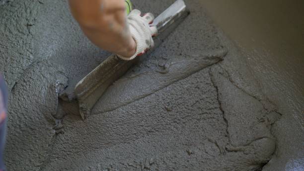 istock Leveling the building mix on the floor with a spatula. A worker spreads the cement mixture over the concrete floor with a spatula. A worker pours a self-levelling screed onto the floor, levels it and smoothes it with a metal spatula, a master builder leve 1414296542