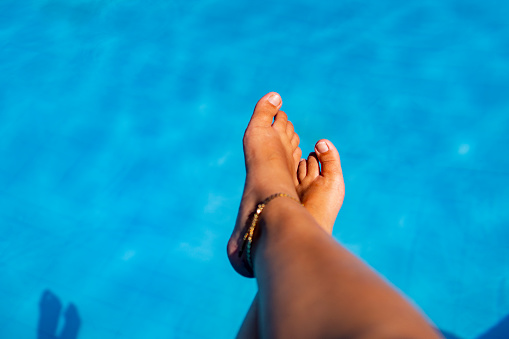 tan wet legs of young woman having summer suntan at swimming pool
