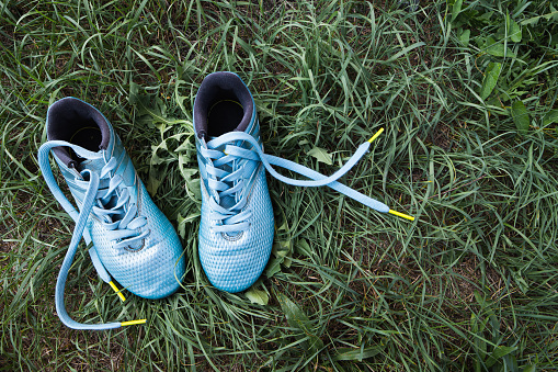Soccer / football children's light blue boots on green grass