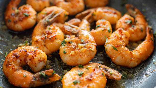 closeup garlic butter shrimp in pan - shrimp pan cooking prepared shrimp imagens e fotografias de stock