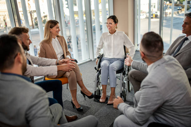 Confident business woman in wheelchair presenting during business meeting with colleagues stock photo