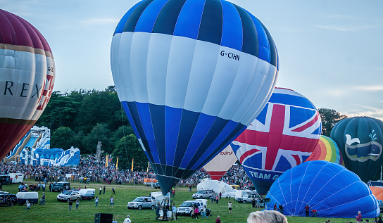 Bristol, UK - August 13, 2016: The Bristol International Balloon Fiesta 2016, showing the mass ascent and landings of over 100 balloons including special shapes and the 'night glow', where the burners are used at night to illuminate the balloons. This annual event takes place in Ashton Park, Bristol.
