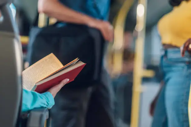 Photo of Cropped shot of a woman hands holding a book in a bus