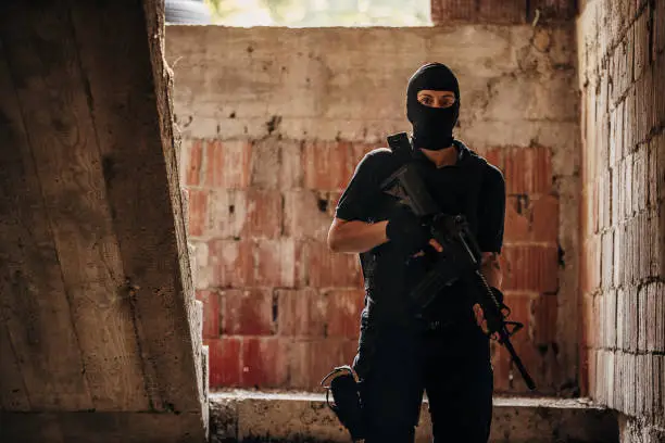 SWAT team female soldier standing on her position with gun on a mission in abandoned building