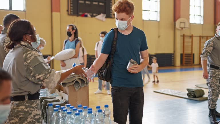 People at emergency shelter receiving supplies from military workers