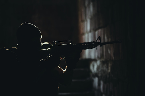 SWAT team soldier standing in the dark on his position with gun on a mission in abandoned building