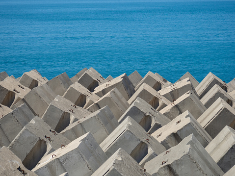 istock Concrete breakwaters and heaps of stones on the shore. Stone against the waves. Shore protection. 1414311577