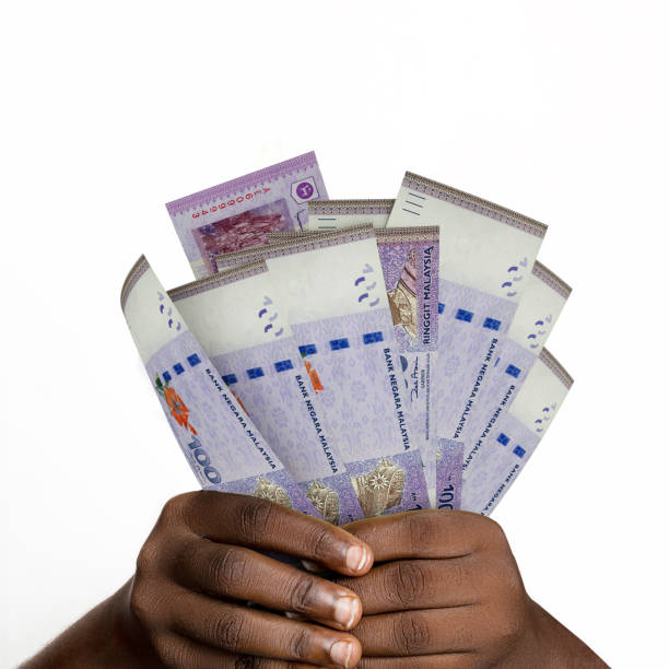 istock Black hands holding 3D rendered 100 Malaysian ringgit notes. closeup of Hands holding Malaysian currency notes 1414312472