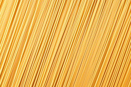 Italian food background, raw spaghetti filling the frame in a textured design of diagonal pasta lines.