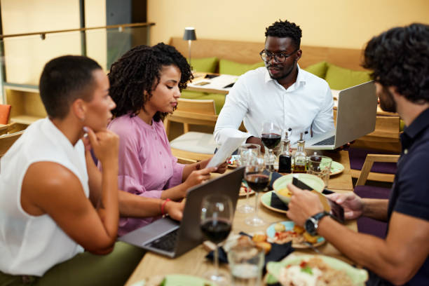 istock Multicultural colleagues sit in a restaurant at business lunch while listening to their boss explaining the project. 1414314539