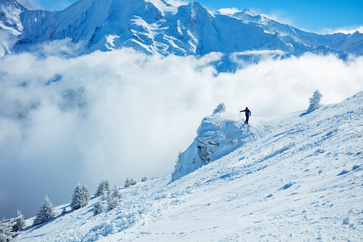 Free-ride skier in fresh powder snow running downhill in beautiful Alpine landscape. Blue sky on background. Free space for text