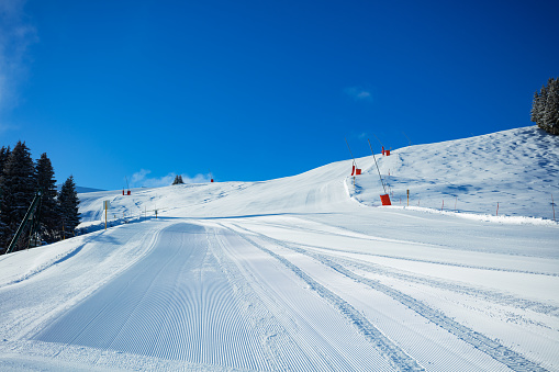 Fresh alpine ski track without people in the sunny morning