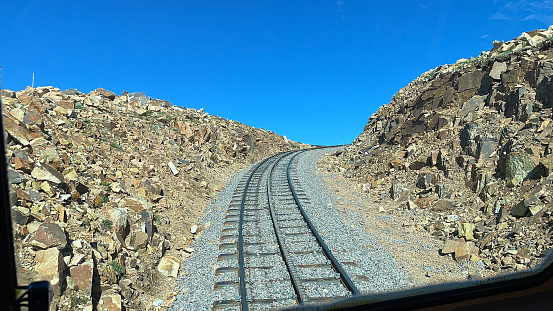 Pikes Peak, Colorado, USA - July 10, 2021: View of the cog railroad tracks seen from inside a cog railroad car on its ascent near Peaks Peak Summit on a clear, sunny day.