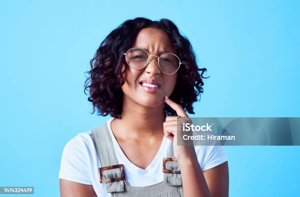 Confused Puzzled And Thinking Woman Having A Bad Idea And Frowning Against Isolated Blue Background Trendy Woman Struggling To Choose Or Make Difficult Decision Pensive Woman Solving A Problem Stock Photo - Download Image Now