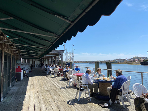 Cape May, USA - April 15, 2022. Tourists dining on deck at Lobster House in Cape May, New Jersey, USA