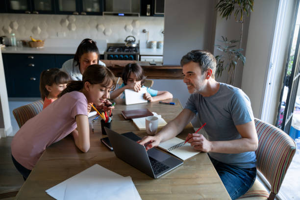 istock Daddy showing something on laptop screen to oldest daughter while mom is with the other younger kids at the end of the table 1414336456