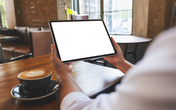 istock Mockup image of a woman holding digital tablet with blank white desktop screen in cafe 1414336708