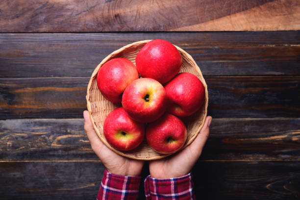 istock Red apple fruit in basket holding by hand 1414338915