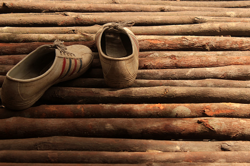 Farmer's shoes lying on the wooden floor after working in the forest.