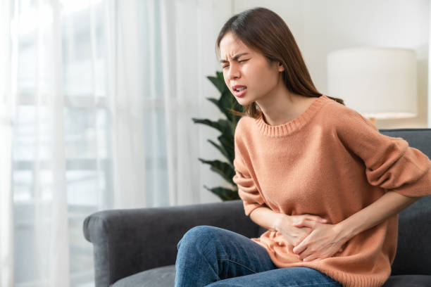 Young Asian woman hands holding the stomach and pain period cramps because having menstruation. stock photo