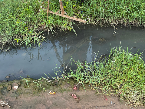 Stock photo showing elevated view of poor sewer drainage on roadside in New Delhi suburbs, India, dirty water unable to go down the road drain.