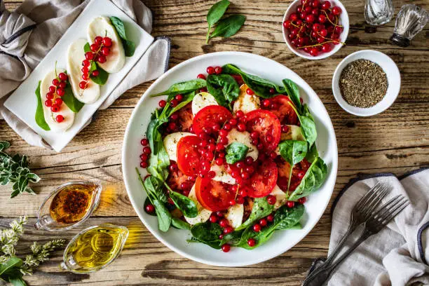 Mozzarella salad with spinach and red currant on wooden background