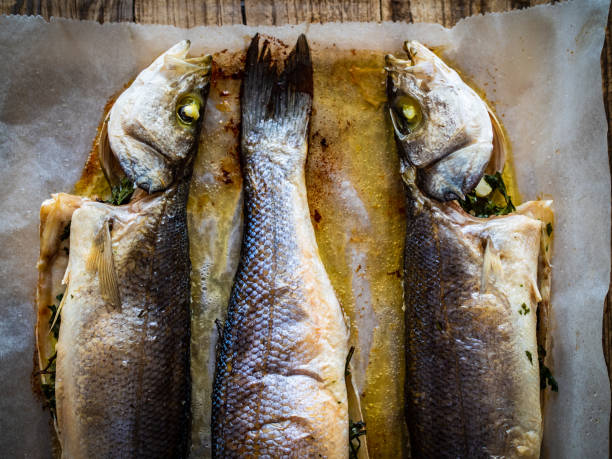 istock Fish dish - roasted trout on baking paper in cooking pan 1414355963