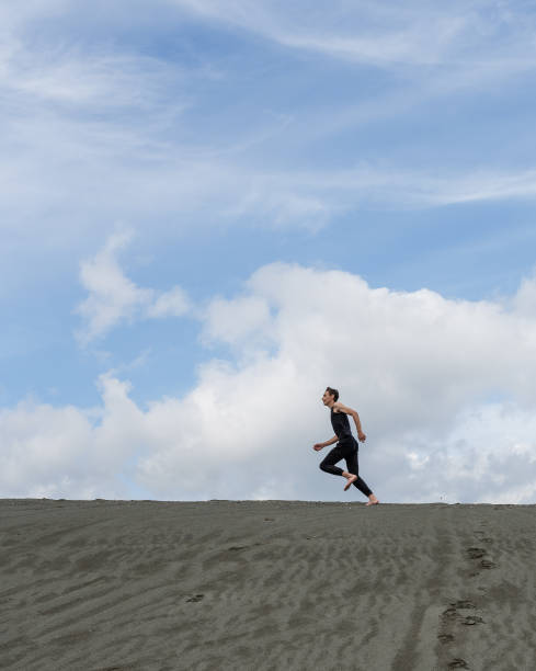 istock Lone man running on the sand through sandy desert 1414356693
