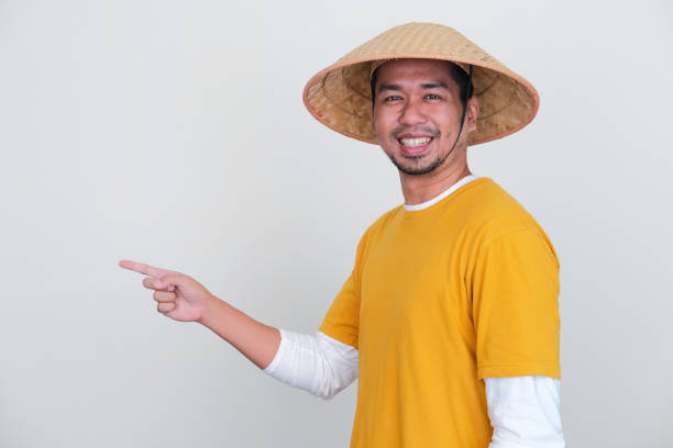 istock Young Indonesian farmer smiling while pointing finger to the right side 1414357766