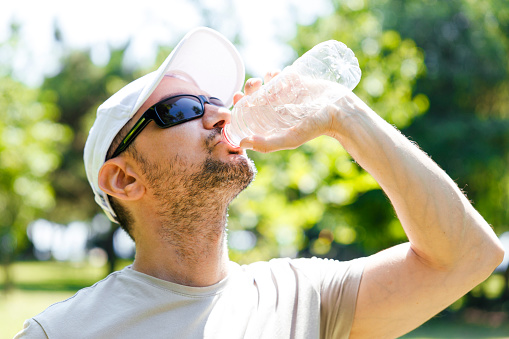 Sporty young man wearing sunglasses drinking water