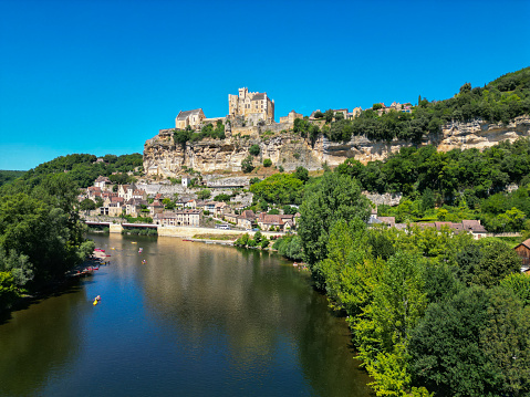 Young people canoing on the Dordogne River in France, past medieval castles and striking ancient cliffs.  The lad in the back of the canoe holds a small camera.  The couple in the canoe are my son and my wife, who would be excited to see their photo in use.  I would appreciate it if anyone using this photo could pm me to say where it is used.  Thanks