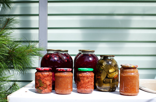 Glass jars with canned homemade jam on table outside