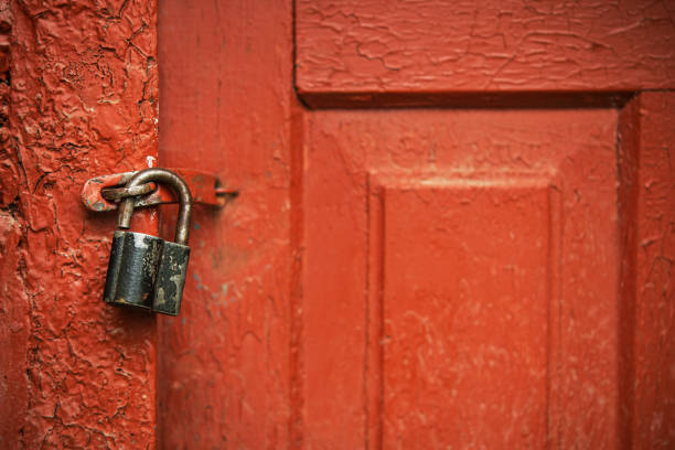 istock Old red painted door with metal open padlock. 1414364586