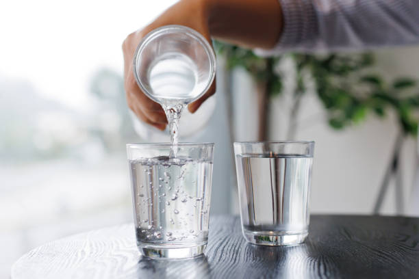 verter agua de la botella en el vaso en un café. - agua purificada fotografías e imágenes de stock