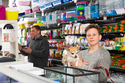 Portrait of a boy with dog in petshop, man on background