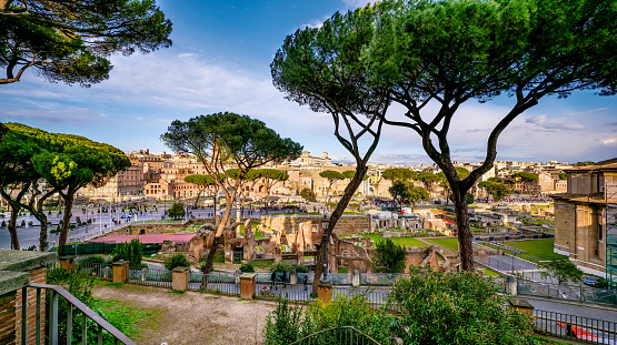 A suggestive and detailed cityscape of the Roman Forum seen from the terrace of the Capitoline Hill or Campidoglio (Roman Capitol), in the historic heart of the Eternal City. In the foreground the Forum of Caesar with the remains of the Temple of Venus Genetrix, while in the background the Forum of Trajan. In the center the Fori Imperiali Boulevard, which connects the Colosseum with the central square of Piazza Venezia. The Roman Forums, one of the largest archaeological areas in the world, represented the political, legal, religious and economic center of the city of Rome, as well as the nerve center of the entire Roman civilization. In 1980 the historic center of Rome was declared a World Heritage Site by Unesco. Super wide angle image in high definition and 16:9 format.
