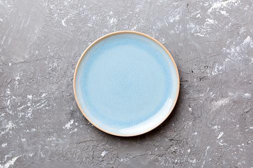 Top view of empty blue plate on cement background. Empty space for your design.