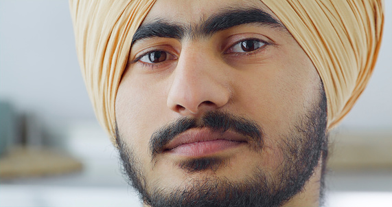 Close-up of Sikh young man wearing turban looking into camera.