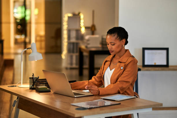 istock Young businesswoman browsing on a laptop while working on a project in an office. A serious female professional checking and sending emails on a pc alone. Corporate boss working overtime at night 1414378884