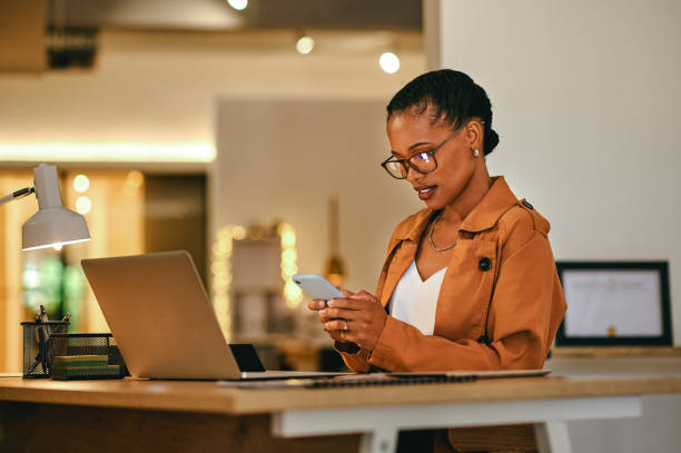 istock Female leader, manager or boss reading a text message on her phone while at work late in her office at night. Trendy, stylish and modern business woman working overtime to meet a corporate deadline 1414378886
