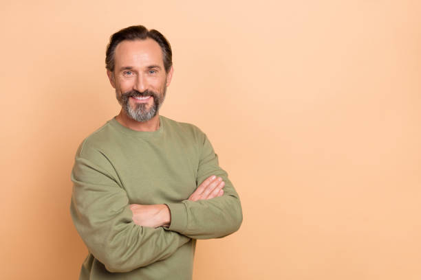istock Portrait of attractive experienced cheerful man folded arms copy empty place space isolated over beige pastel color background 1414382673