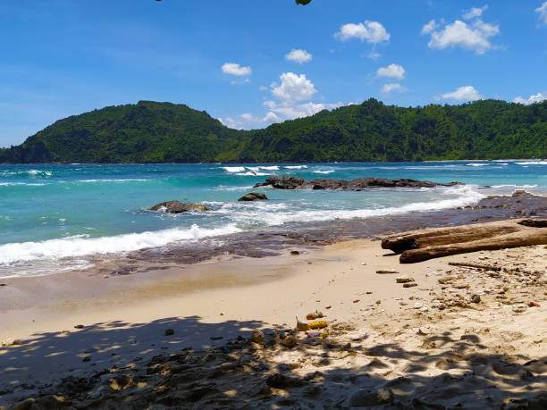 istock white sand beach with black rocks and two green mountains. Beautiful natural scenery 1414383863