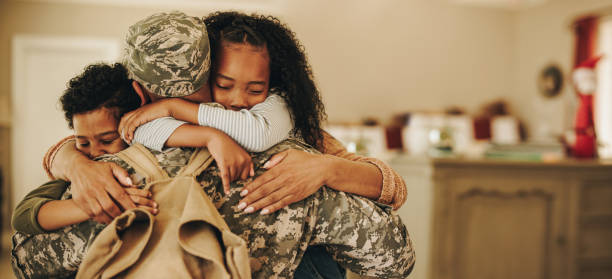 Soldier embracing his wife and kids on his homecoming Soldier embracing his wife and kids on his homecoming. Serviceman receiving a warm welcome from his family after returning from deployment. Military family having an emotional reunion. military stock pictures, royalty-free photos & images