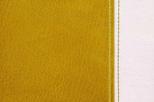 Natural, artificial yellow and white leather texture background with vertical decorative seam. Material for sport items, clothes, furnitre and interior design. ecological friendly leatherette.