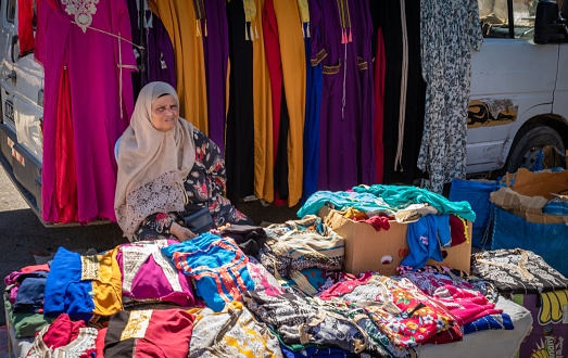 An elderly woman sells woman's clothing at the Sunday Souk, a aeekly market in Sousse, Tunisia.