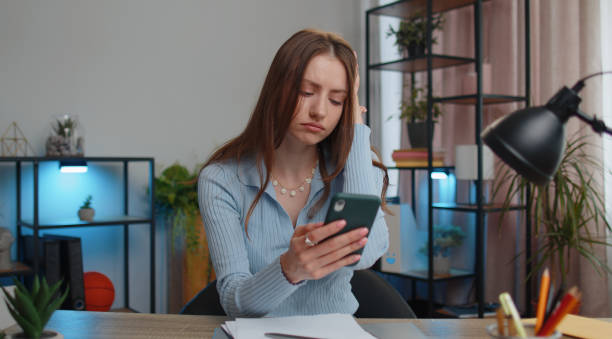 une femme de bureau d’affaires utilise un smartphone perd, surprise par des résultats de loterie soudains, une mauvaise fortune, une perte - pleading women business sadness photos et images de collection