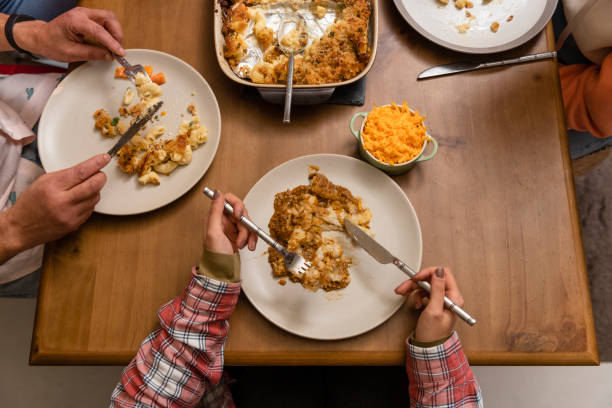 A high angle view of an unrecognisable family eating a meal at a dining table at home in Northumberland, North East England. They are in the middle of eating.