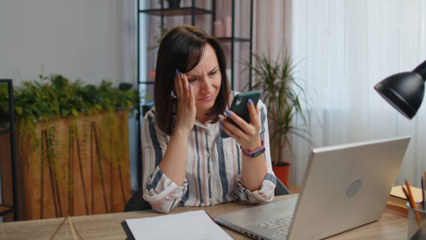 une femme de bureau d’affaires utilise un smartphone perd, surprise par des résultats de loterie soudains, une mauvaise fortune, une perte - pleading women business sadness photos et images de collection