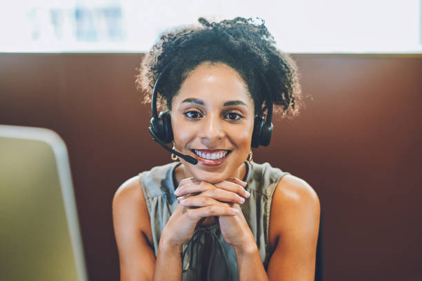 istock Happy, friendly and helpful call center agent smiling while wearing a headset and sitting in office. Confident businesswoman consulting and operating helpdesk for customer sales and service support 1414393922