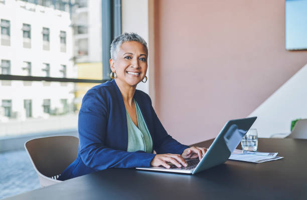 Senior business woman typing on laptop, replying to emails and working on a proposal in an office at work. Portrait of a mature female boss, manager and ceo browsing the internet and planning online stock photo